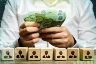 © Andrii Yalanskyi - Adobe Stock.com figure_photo: Figuren auf Würfeln und Hände mit Geldscheinen