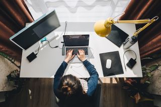 figure_photo: Frau sitzt im Homeoffice beim Schreibtisch und arbeitet am Laptop