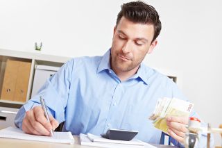 figure_photo: Mann mit Stift und Geldscheinen in den Händen